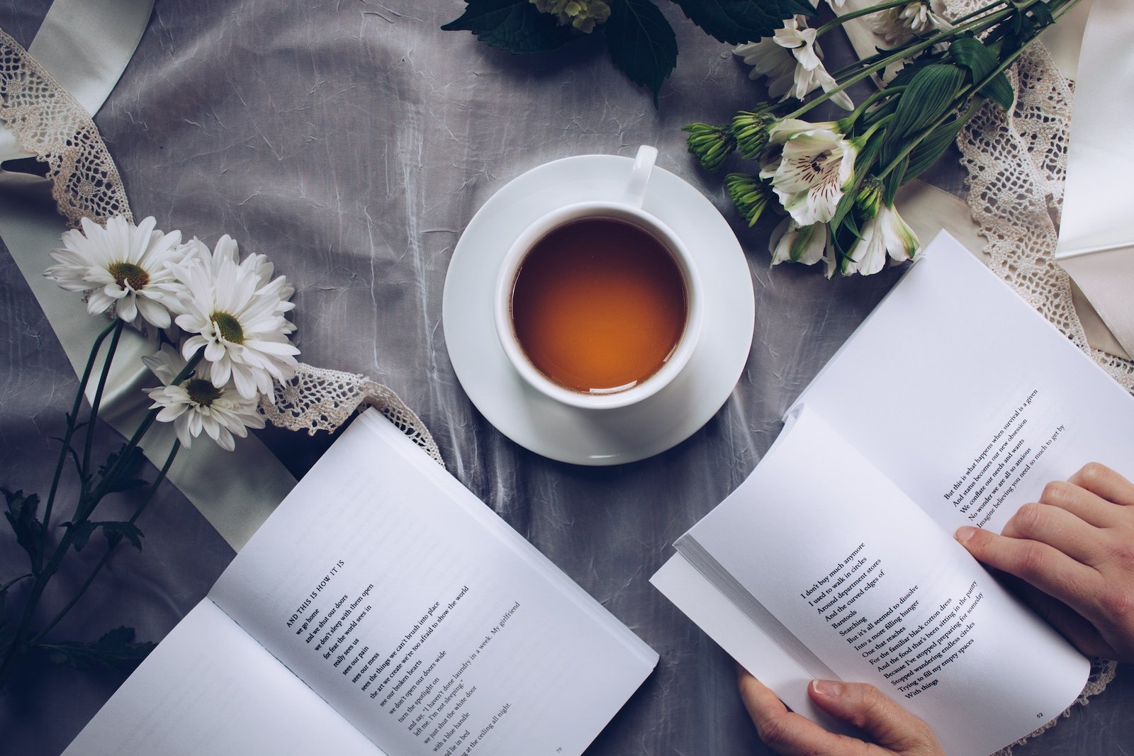 white-ceramic-teacup-with-saucer-near-two-books-above-gray-floral-textile